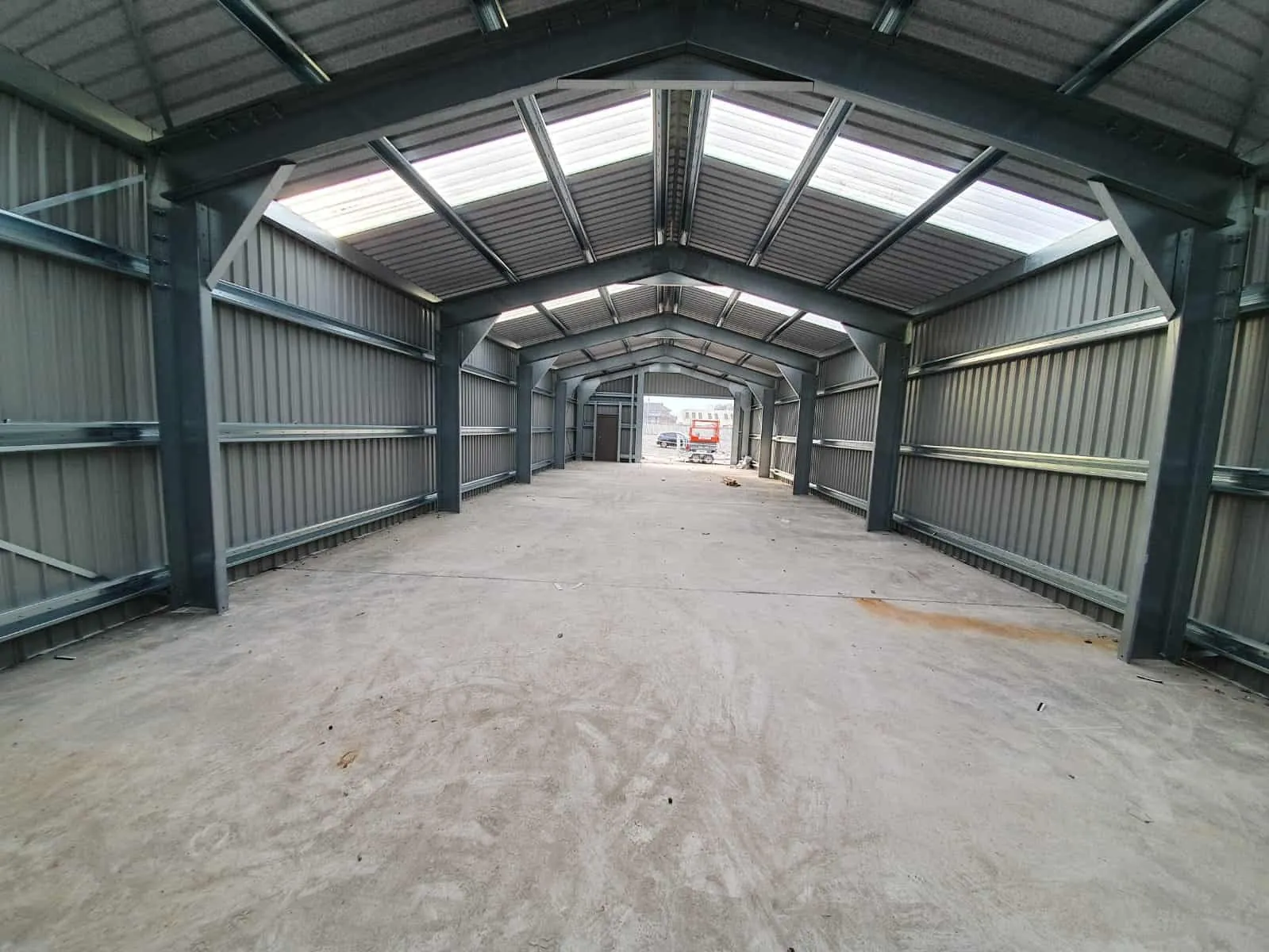 Inside a clear span steel building with roof lights and a concrete floor