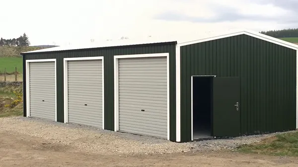 Three bay steel garage with white roller doors and green cladding